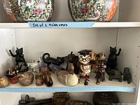 Shelf with various small animal figurines including cats, dogs, birds, sheep, owl piggy bank, and Saint Bernard piggy bank.