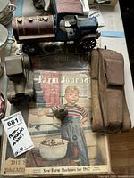 Photo showing three antique metal toy vehicles on top of the Farm Journal magazine from January 1947, highlighting the toy designs and magazine cover illustration.