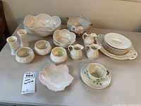 All items displayed on table showing variety of ceramic pottery including bowls, plates, creamers and a teacup.