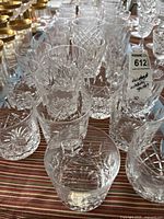 Overview of various cut glass tumblers and glasses in different patterns and sizes, arranged on cloth surface.
