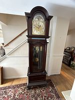 Full view of tall clock showing arched bonnet top, glass door, fluted columns and base molding