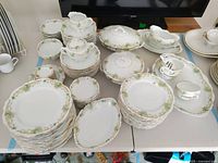 Full overview of the Royal Austria dinner set with dinner plates, salad plates, small bowls, creamers, sugar bowls, and covered serving dishes laid out on tables.