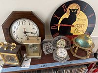 Overview of all clocks and small brass globe on stand on shelf
