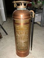 Front side view of the copper vintage The Buffalo fire extinguisher showing embossed brass label with instructions and branding.