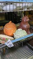 Group photo of ceramic jars and platters on metal shelf showing cabbage jar, carrot jar, cat cookie jar, and floral and white platters