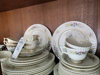 Full view of stacked Lenox Sonnet china set with plates, cups, and saucers showing floral pattern and gold accents