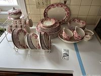 Overall view of all pieces on countertop including racks, stacks of plates, cups, sugar bowl, creamer, and platter