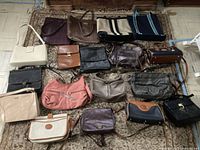All handbags arranged on a rug, showing variety of colors and styles