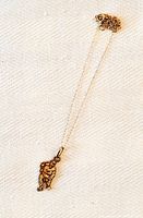 Pendant hanging on delicate chain displayed on white textured fabric