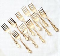 Set of 10 ornate silver-plated dessert forks laid out showing decorative handles and tines.