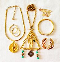 All costume jewelry items laid flat on white fabric background including necklaces, bracelets, earrings, brooch
