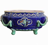 Front view of the antique Victorian majolica jardiniere planter showing cobalt blue body, green scroll handles, and decorative bird motifs.