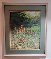 Frontal view of the painting showing red Indian paintbrush flowers, green foliage, framed in a light wood frame with a green matting.