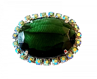 Close-up top view of the vintage brooch showing the large central green glass stone surrounded by iridescent rhinestones in silver-tone metal setting.