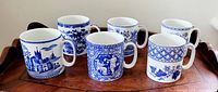 Six blue and white Spode mugs shown together on a wood tray, each with unique blue design patterns.