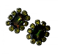Front view of both green topaz rhinestone clip-on earrings showing square center stones and surrounding round stones with reflective green hues, set in japanned metal.