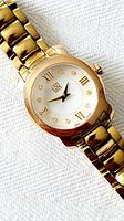 Close-up front view of gold plated ESQUIRE women's wristwatch with diamond hour markers and Roman numerals on white dial.