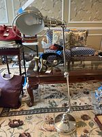 Full view of chrome floor lamp with adjustable arm and swivel mechanism, positioned in a room with carpet and furniture.