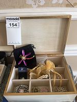 Overview of open jewelry box containing multiple pins, hair accessories, and pouches including Swarovski branding