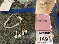 Photo showing CZ tennis bracelet, dangling earrings with white beads, and boxed blue stone earrings.