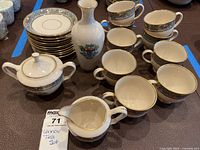 Overview of nine teacups, eleven saucers, sugar bowl, creamer and small base piece on table