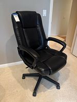 Front angle view of the black office chair showing high backrest, cushioned seat and armrests, and five caster wheels on the base.