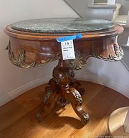 Full view of the table showing marble top, wood frame and pedestal base