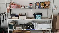 Full view of three shelves showing assorted tools, wires, faucet sets, BD power drill and sander, small cooler, and other hardware items.