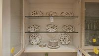 Three-shelf display cabinet showing all plates in lot