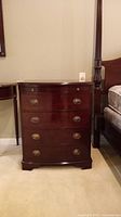 Front view of wood chest with four drawers showing brass oval pull handles and visible repair on first drawer.