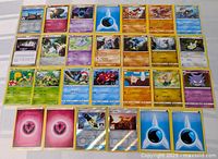 Photo showing 26 Pokémon cards spread out in rows, including Pokémon, Trainer, and Energy cards, some holo/foil