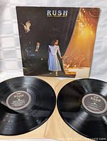 Front cover of Rush Exit...Stage Left album with two vinyl records laid out in front.