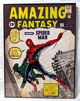 Clear photo of the framed poster showing the iconic Amazing Fantasy #15 cover featuring Spider-Man swinging with a man in his web. The poster is behind glass and the frame is visible.
