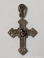 Front view of sterling silver cross pendant with marcasite stones and central purple stone.