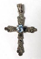 Front view of sterling silver cross pendant with marcasite stones and central light blue faceted gemstone, detailed texture visible.