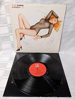 Vinyl record album with cover showing illustrated woman reclining on outline of a car, with record partially removed showing red label.