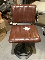 Front view of the brown faux leather barstool showing padded seat and backrest with vertical stitching.