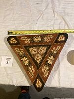 Photo of the top of the triangular antique music box showing detailed inlaid wood floral patterns and measurement tape indicating size