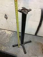 Side view of cast iron and steel bar table base with measuring tape showing height around 40 inches