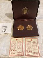 Two gold plated collectible medals displayed in a presentation case with certificates of authenticity.