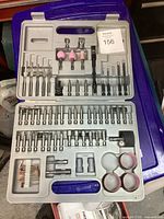 Full view inside open plastic case showing an organized set of Dremel drill bits, sanding drums, and grinding stones.