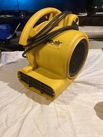 Yellow Shop-Air 500 air blower fan placed on white surface, clearly showing front side outlet vent, sturdy handle, and power cord wrapped around.