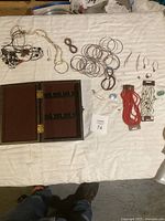 Full overview of the lot showing a jewelry box, multiple necklaces, metal bangles, earrings, bracelets, and rings spread on a white cloth.