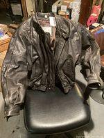 Black leather jacket on chair showing front and sleeves.