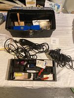 Lot of pet grooming tools including black toolbox containing brushes and grooming accessories, electric clippers with cords.