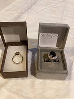 Two rings displayed side by side in separate boxes (brown and gray), top-down view