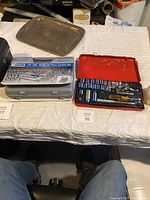 Overview of two socket sets and a metal tray on a white surface