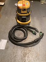 Full view of Johnny Vac vacuum cleaner and black hose coiled beside it on the floor.