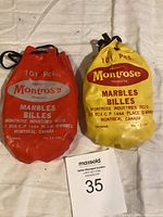 Two vintage Montrose marbles pouches, one red and one yellow, side by side showing brand and labeling details.