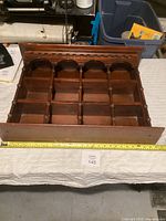 Full view of the wooden wall hanging shelf showing compartments and spindles with a measuring tape for width reference